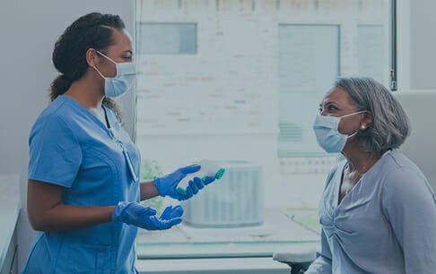 Masked provider talks with a masked patient to begin countering vaccine hesitancy