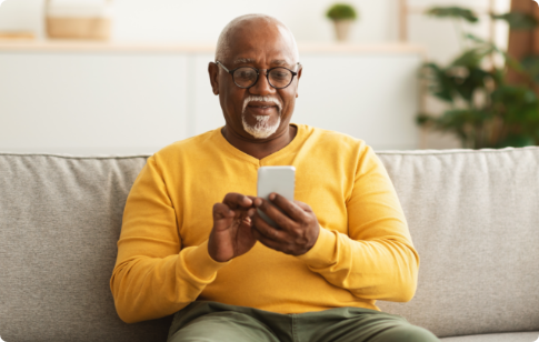 Older man sitting on couch while filling out PAM survey on mobile phone