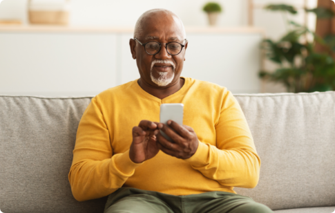 Pam_overview_image1 Older man sitting on couch while filling out PAM survey on mobile phone