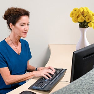 front-desk staffer on computer working on patient scheduling