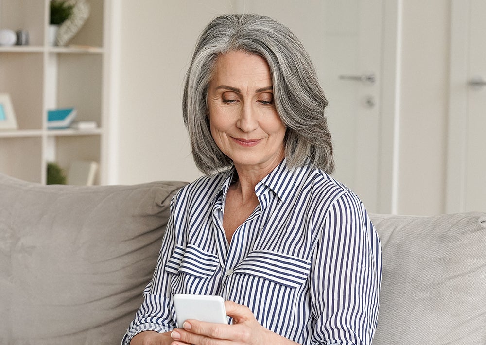 Benefits awareness report. Image depicts an older woman sitting on a couch, looking at her mobile phone.