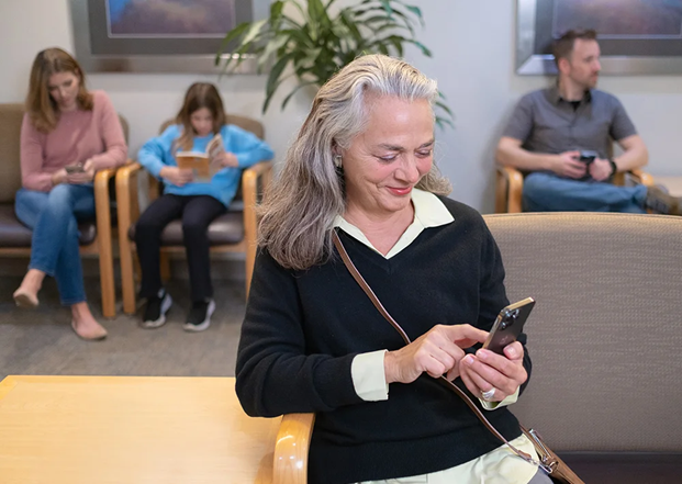 woman in waiting room completing patient intake on mobile phone