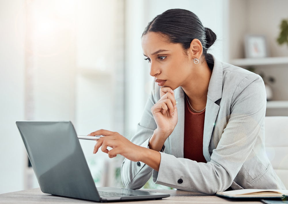 A photo of a healthcare professional reading something on a laptop.