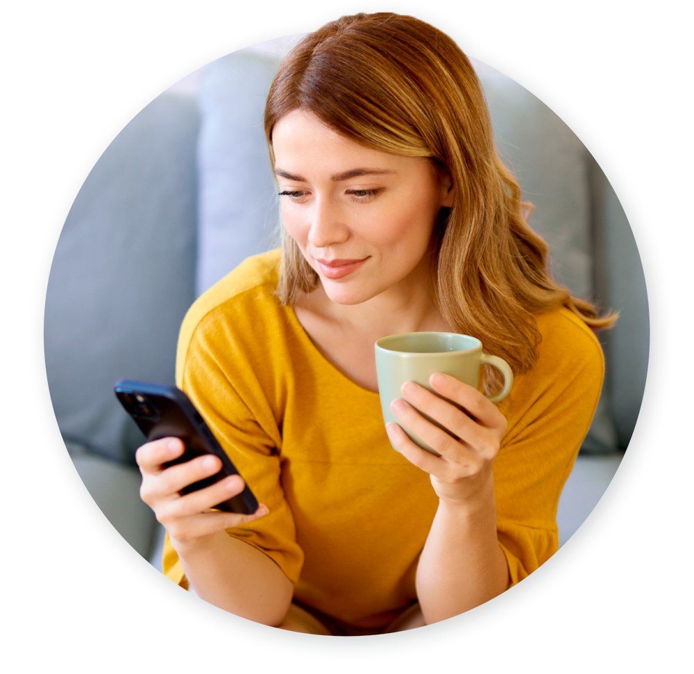 Patient looking at her phone on couch while drinking coffee