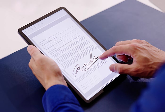 A photo of someone digitally signing a form on a tablet.