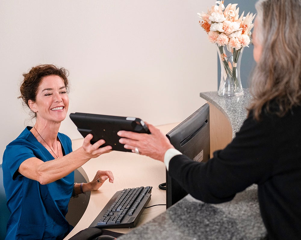 PHR - Blog Image - Onsite AEO 4 V1 250718 Front desk handing ipad to patient