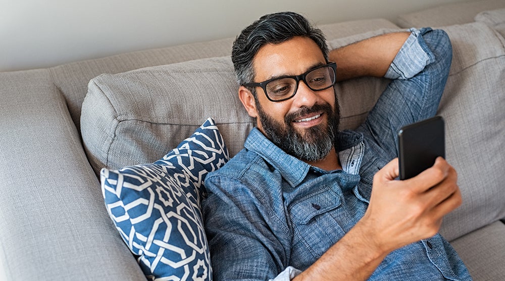 Man on couch with phone, smiling