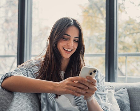 Young woman sitting on couch and looking at phone