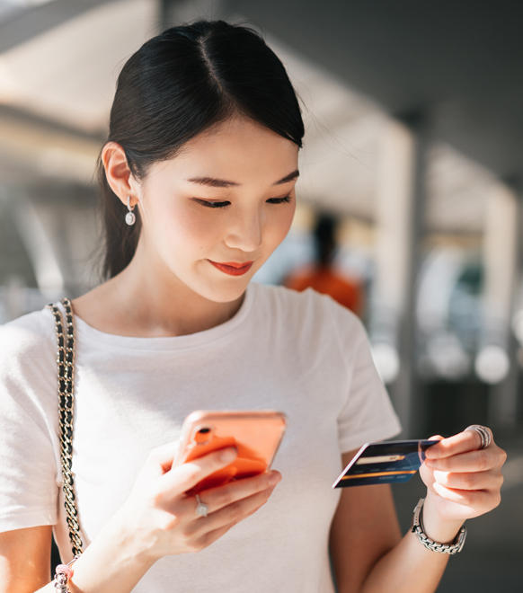 Woman making payment over mobile phone and holding credit card