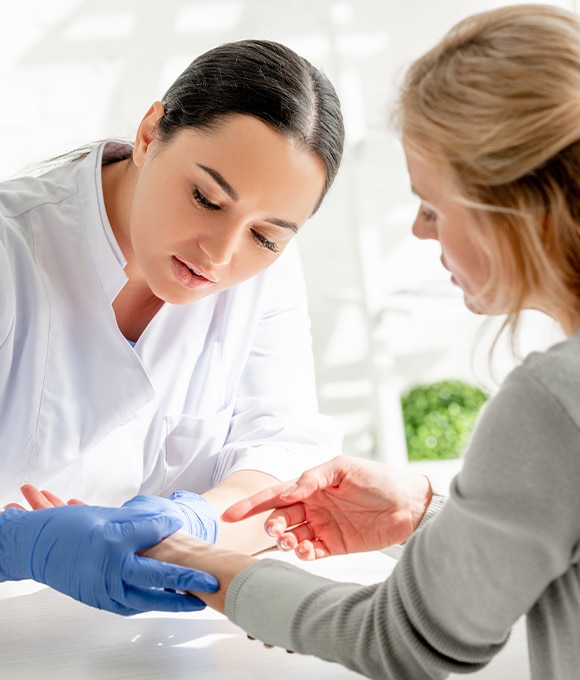 Female healthcare provider looking at wrist of female patient