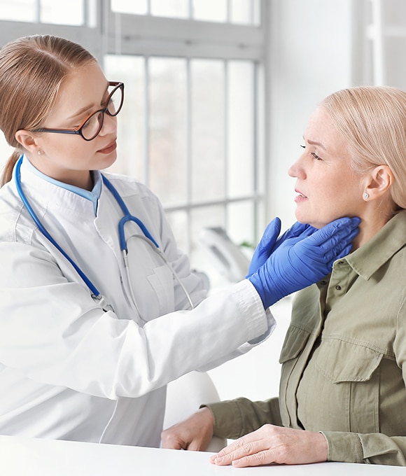 Female doctor feeling thyroid of female patient
