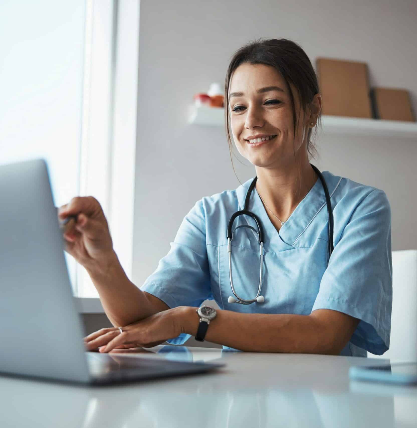 Doctor at her desk smiling on laptop