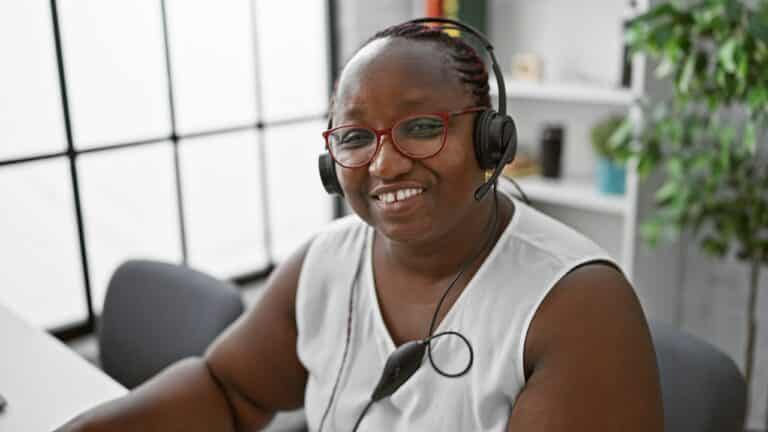 African American woman happily working at computer with headset