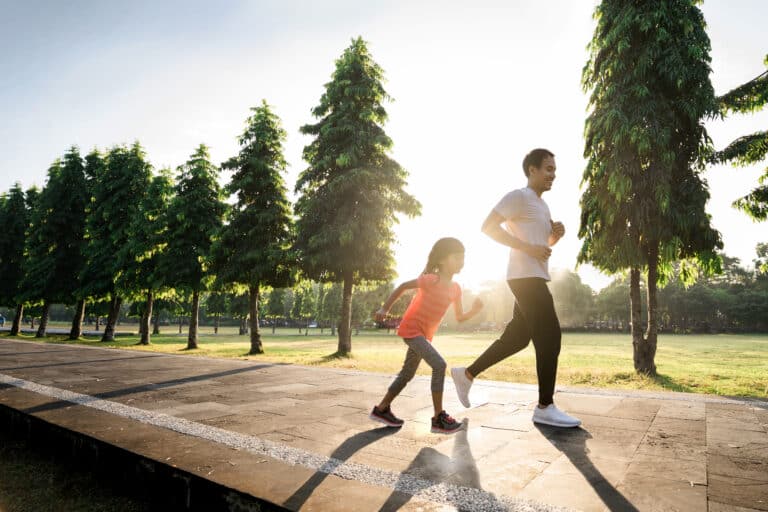 Dad and daughter running on path outside