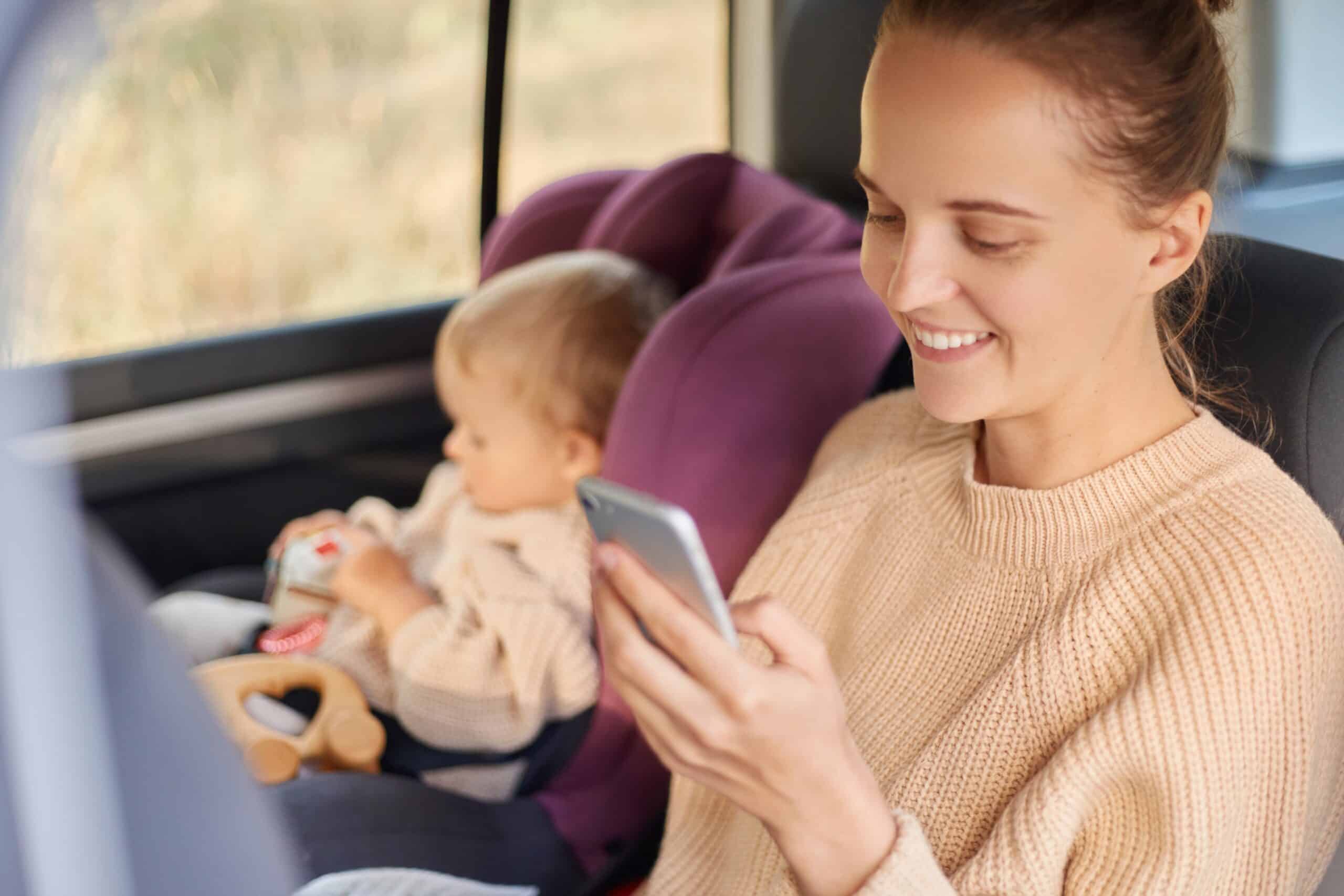 Mother and child stopped in car looking at phone